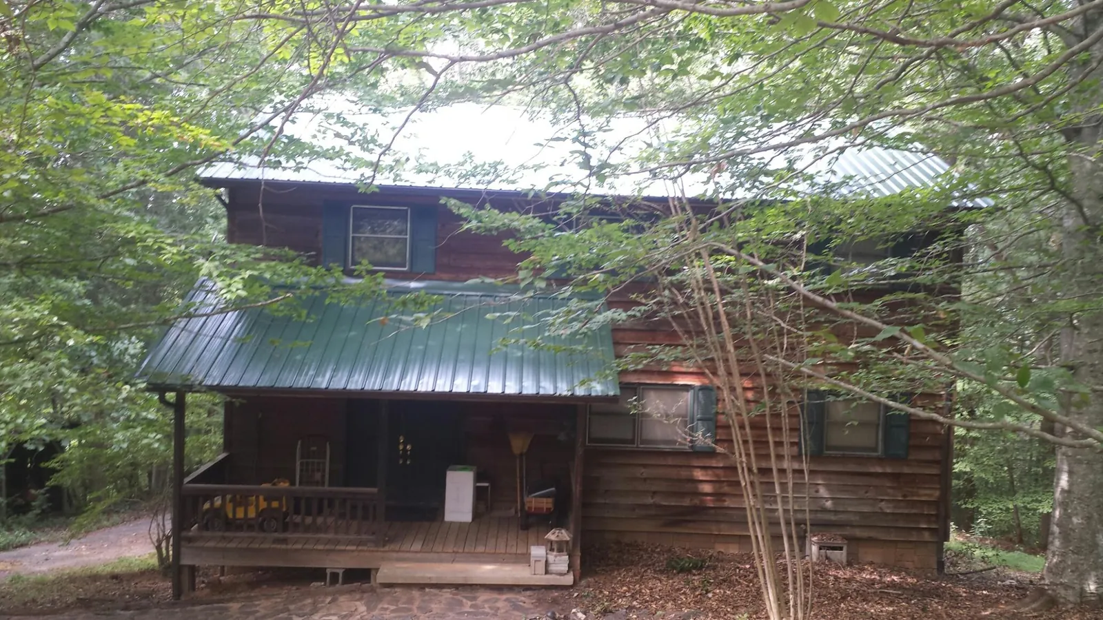 Green metal roof and covered porch on a log cabin in Renton