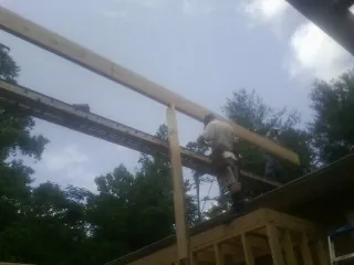 Carpenter setting a ridge beam over a new addition frame — Ice Dam Removal by Roofing Brothers in Renton