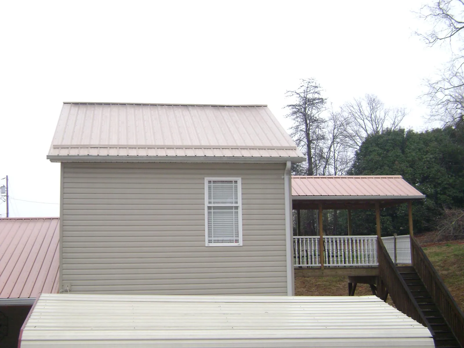 Tan metal roofs on a two story addition and attached porch, from a Roof Replacement job in Renton