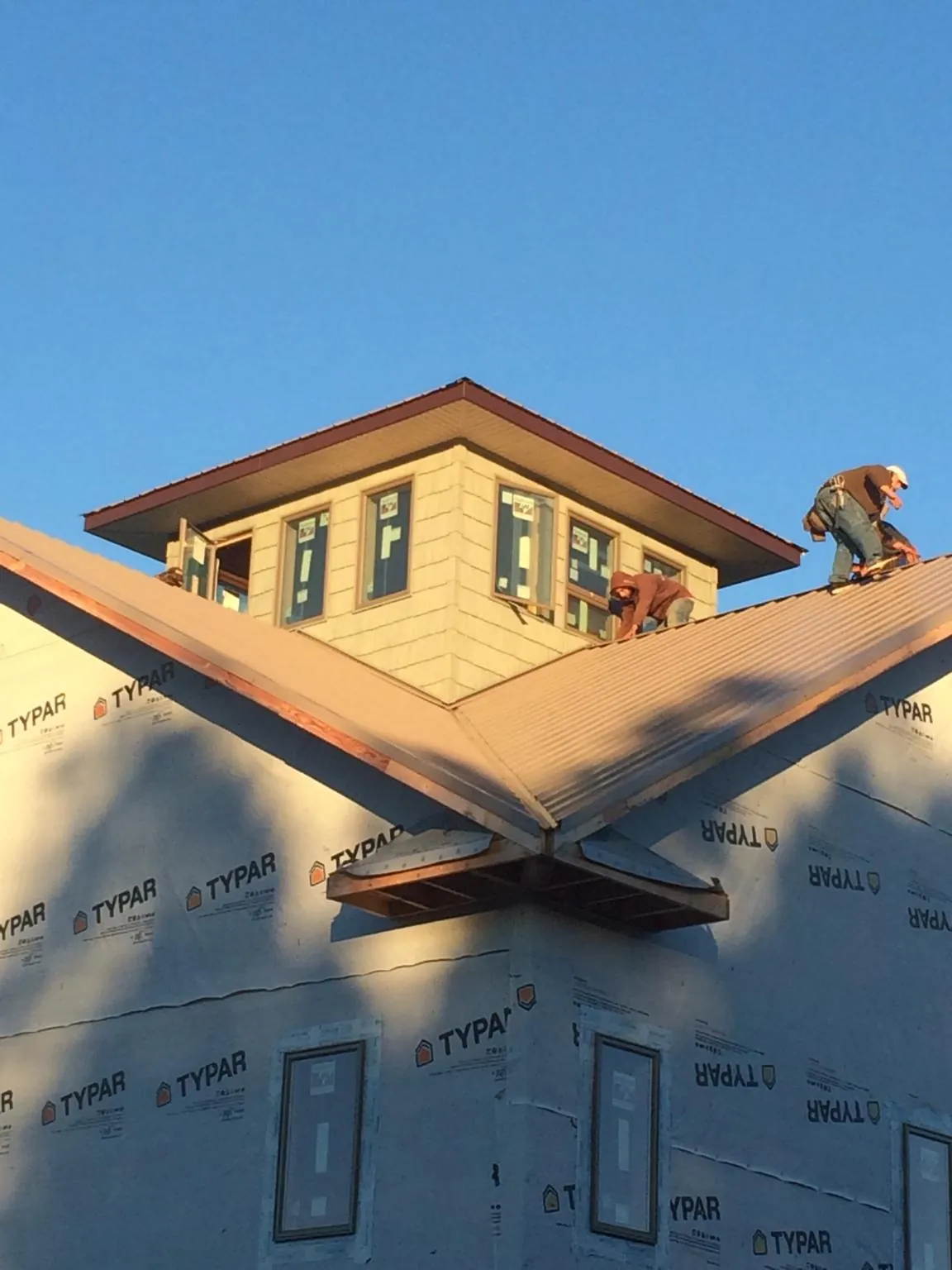 Roofers working around a rooftop cupola on a new metal roof at sunset — Roof Waterproofing in Renton by Roofing Brothers